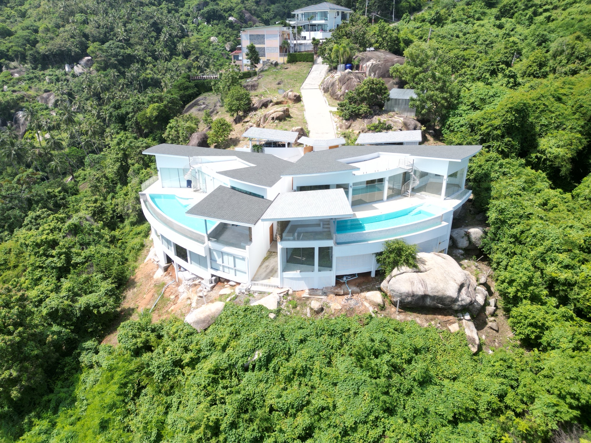 Aerial view of the first villa, its curved roofs and infinity pools wrapping the ridge